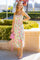 woman wearing a floral midi dress with a sweetheart neckline and side slit, holding a pink handbag