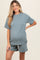 woman wearing a cozy ribbed maternity set in teal with a loose top and shorts, showcasing her baby bump