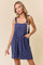 woman wearing a navy blue ribbed romper with adjustable straps and side pockets