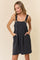 woman wearing a black and white striped pinafore dress with pockets and button details