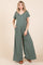 woman wearing a green striped short sleeve jumpsuit with pockets and wide legs, styled with brown sandals