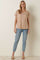 woman wearing a beige v-neck t-shirt with a pocket and light blue jeans, standing on a neutral background
