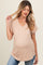 woman wearing a light beige short sleeve maternity top with a v-neck and pocket, showcasing her baby bump