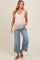 woman wearing a nude maternity tank top and light blue wide-leg jeans, showing her baby bump