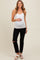 woman wearing a white maternity tank top and black ripped maternity jeans, holding her baby bump