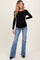 woman wearing a black long sleeve maternity top and flared blue jeans, showing her baby bump