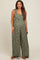 woman wearing a green floral maternity jumpsuit with wide legs and adjustable straps, showcasing her baby bump