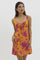 woman wearing a bright orange floral print mini dress with a tie detail at the chest and spaghetti straps