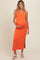 woman wearing a bright orange ribbed maternity dress with a side slit and holding her baby bump