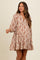 woman wearing a cream and rust printed maternity dress with a flowy silhouette and long sleeves