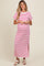 woman wearing a white and pink striped maternity maxi dress with a side slit and holding her baby bump