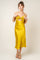 woman wearing a yellow satin midi dress with a bow detail and spaghetti straps