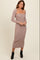 woman wearing a taupe ribbed midi dress with long sleeves and a straight neckline, styled with black ankle boots