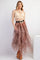 woman wearing a sheer long sleeve top with a beige bralette and a tiered brown tulle maxi skirt, accessorized with a statement belt