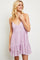woman wearing a light purple sundress with a ruffled hem and a fitted bodice, standing and smiling