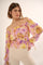 woman wearing a purple and yellow floral off-the-shoulder top with a smocked waist and long sleeves