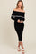 woman wearing a black off-the-shoulder ribbed midi dress with white trim details and white sandals