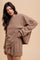 woman wearing a brown checkered oversized sweatshirt and matching skirt with a playful ruffle hem