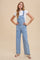woman wearing a light blue denim overall with wide legs over a white t-shirt and white sandals