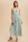 woman wearing a floral maxi dress with a ruffled detail and a rose accent, styled with strappy heels