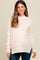 woman wearing a light blush maternity sweater with a relaxed fit and a baby bump visible