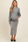woman wearing a gray maternity sweater and matching skirt, gently cradling her baby bump