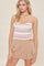 woman wearing a pink and white striped strapless top with a ruffled hem and beige high-waisted shorts