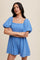 woman wearing a light blue puff sleeve romper with a square neckline and a pink choker necklace