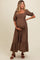 woman wearing a brown floral maternity dress, standing with her hand on her baby bump