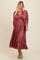 woman wearing a dusty rose long sleeve pleated midi dress with a knotted waist detail and open neckline