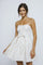 woman wearing a strapless white floral party dress with a bow at the waist