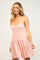 woman wearing a pink gingham print mini dress with a fitted bodice and flared skirt
