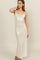 woman wearing a shimmery silver spaghetti strap maxi dress with a draped neckline and fitted silhouette