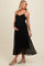 woman wearing a black maternity dress with a pleated skirt and embellished details, showing her baby bump