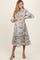 woman wearing a floral print maternity dress with a tiered skirt and a keyhole neckline, cradling her baby bump