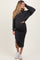 woman wearing a dark gray maternity two-piece set with a cropped sweater and a midi skirt, showing her baby bump