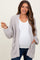 woman wearing a light grey chunky knit maternity cardigan over a white top, showing her baby bump