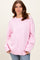 woman wearing a light pink oversized sweater with ribbed details and long sleeves, paired with blue jeans