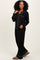 woman wearing a black pajama set with white piping, featuring a button-up top and loose-fitting pants
