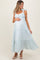 woman wearing a light blue and white striped maternity dress with ruffled tiers and bow straps, cradling her baby bump