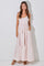 woman wearing a pink floral maxi dress with smocked bodice and tiered skirt, standing with hands in pockets