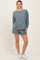 woman wearing a blue checkerboard print long sleeve top and matching shorts with white sneakers