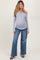 woman wearing a gray long sleeve henley maternity top and distressed wide-leg jeans, showing her baby bump