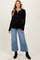 woman wearing a black ribbed maternity top with button details and light wash wide-leg jeans, showing her baby bump