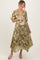 woman wearing a green floral maternity dress with gold accents and a visible baby bump