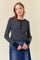 woman wearing a black and white striped long sleeve top with buttons and a scoop neckline paired with a denim skirt