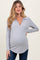 woman wearing a light gray long sleeve maternity top with a collar and a visible baby bump