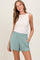 woman wearing a white sleeveless top and mint green casual shorts with side pockets
