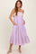 woman wearing a lavender sleeveless maxi dress with lace bodice and ruffled hem, posing with pockets