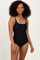 woman wearing a black one-piece swimsuit with a decorative neckline and a form-fitting silhouette